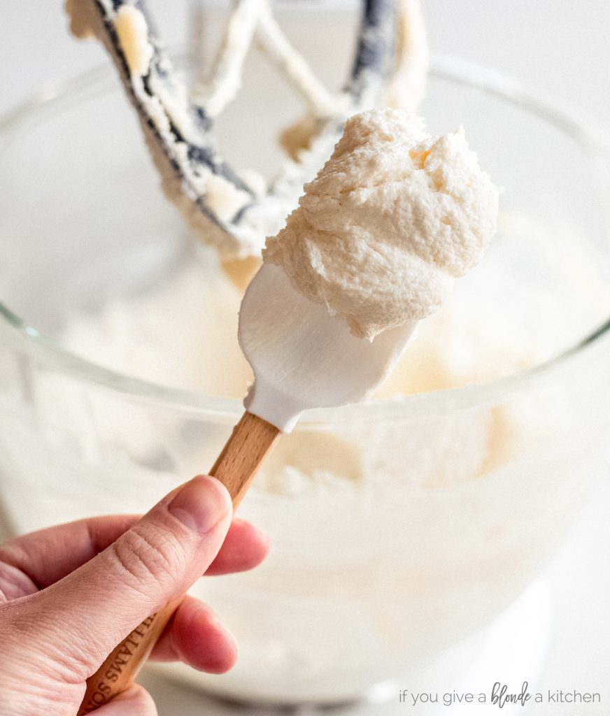 hand holding spatula of light fluffy sugar butter mixture