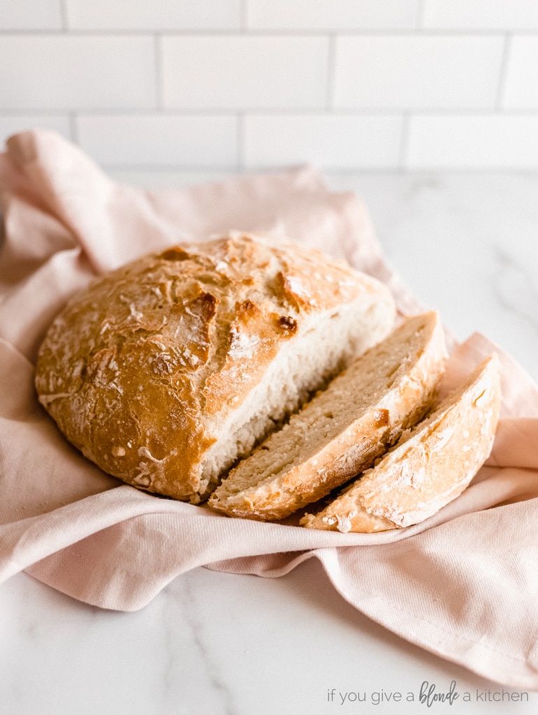 artisan bread with two slices removed on pink kitchen towel