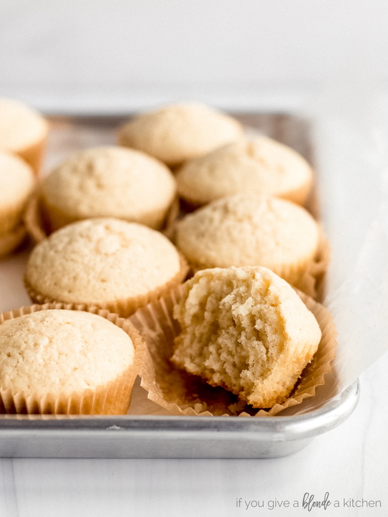 muffin half on paper liner in baking sheet with plain muffins