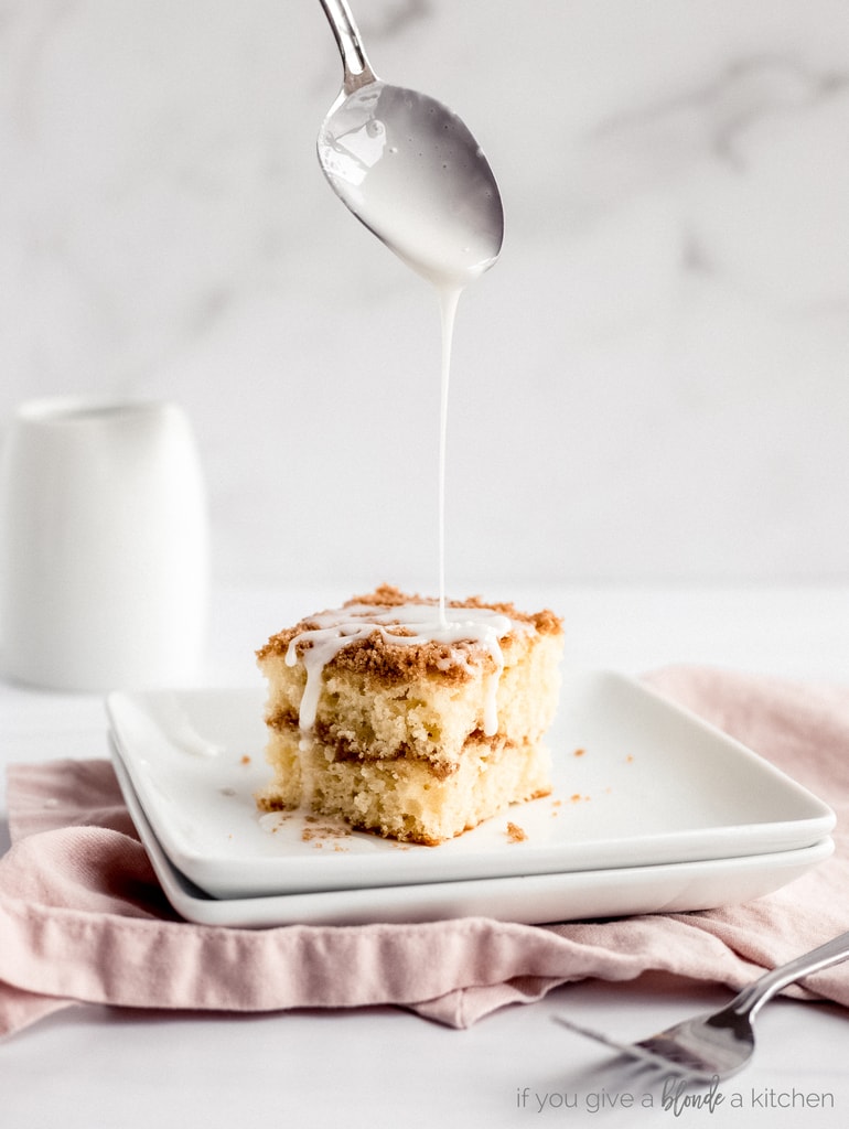 spoon drizzling icing over slice of coffee cake