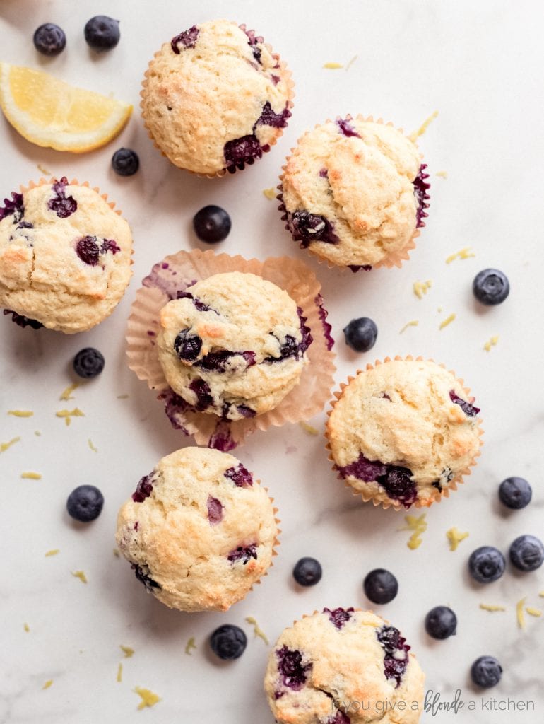 blueberry muffins on marble surface with fresh blueberries scattered