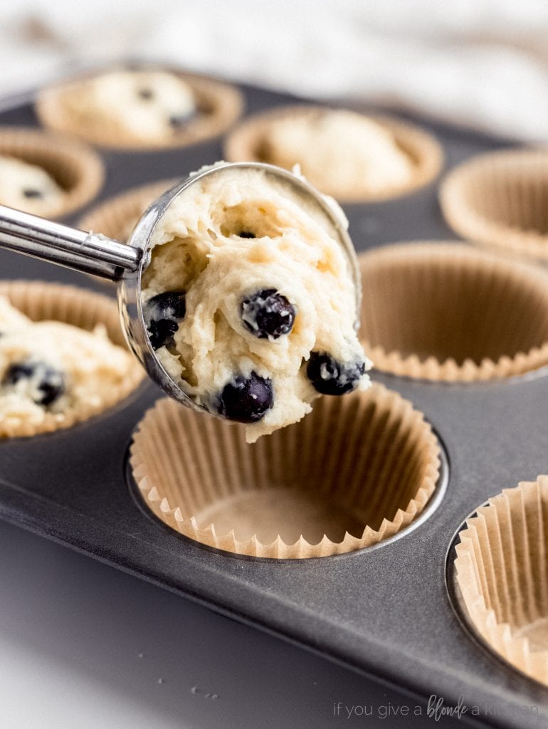 blueberry muffin batter scooped into muffin tin