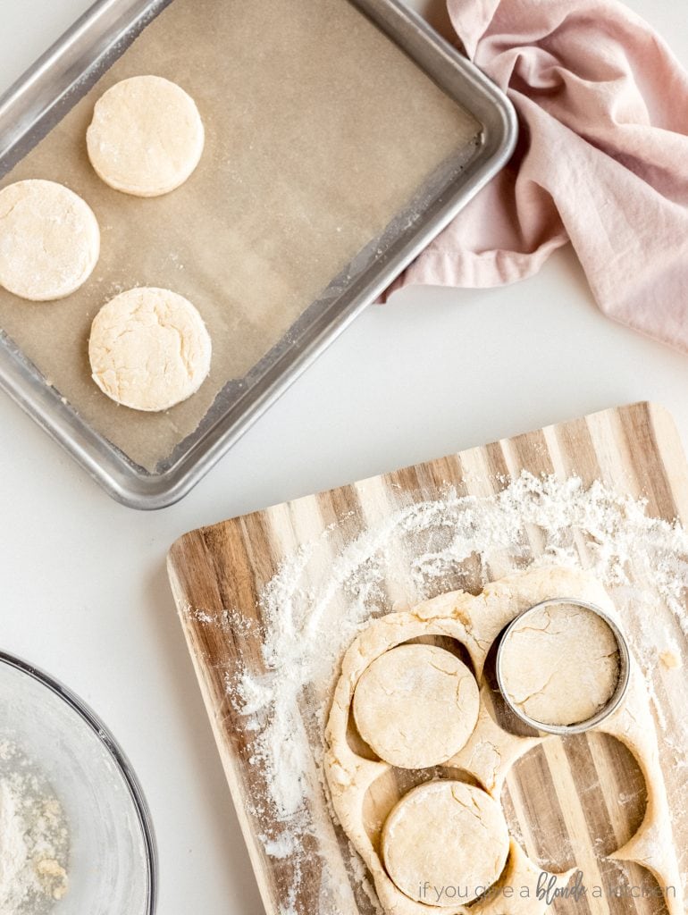 cutting board with flour and biscuit dough; baking sheet with biscuits