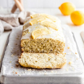 lemon poppyseed bread on parchment paper and baking sheet. end cut off showing inside of loaf.