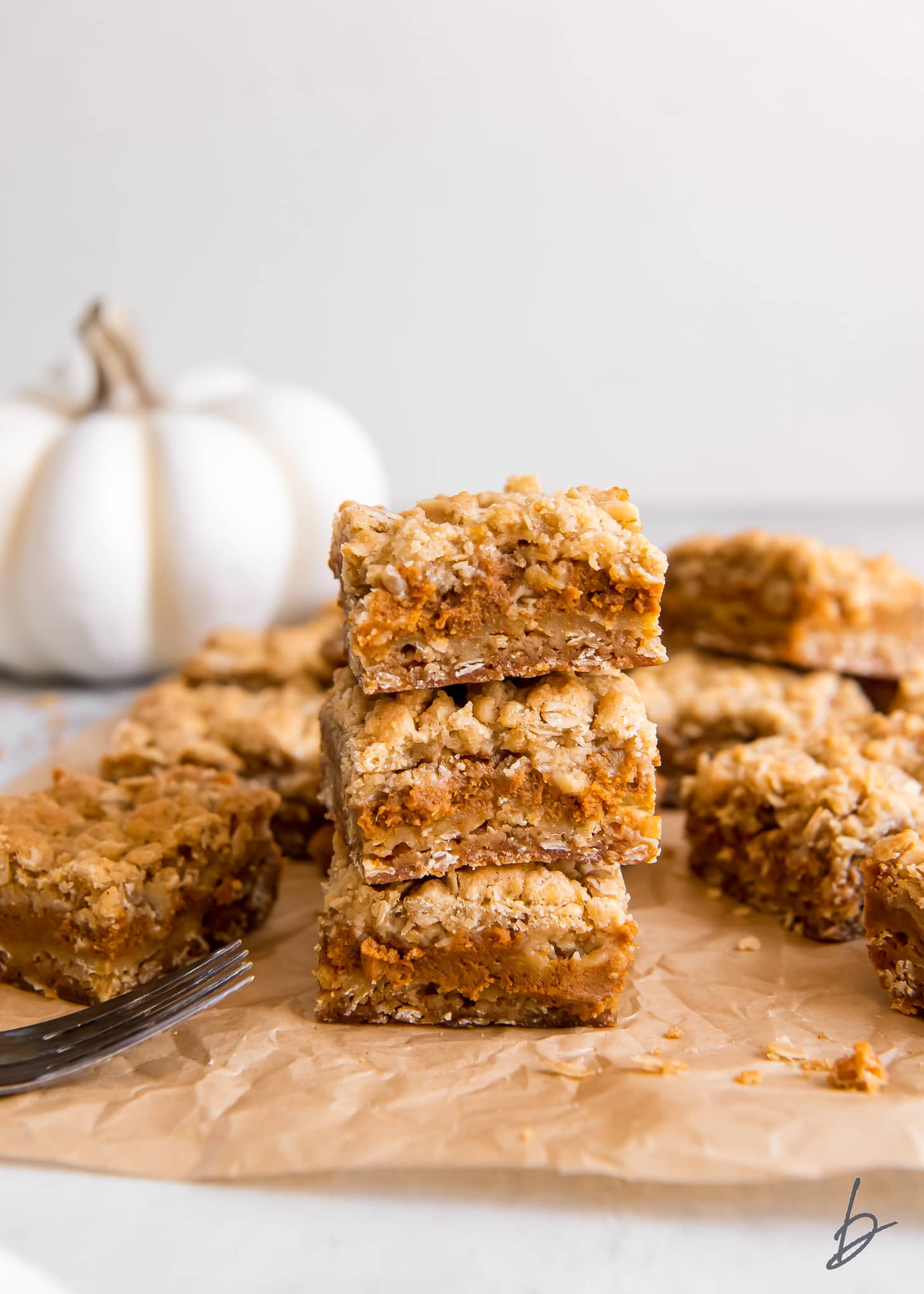 stack of three pumpkin pie bars with streusel on parchment paper.