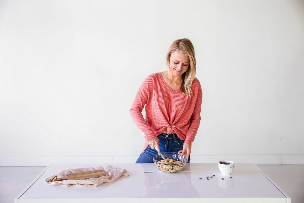 blonde baker where pink shirt and jeans stirring bowl of cookie dough