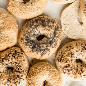 homemade bagels with different toppings, one bagel cut open