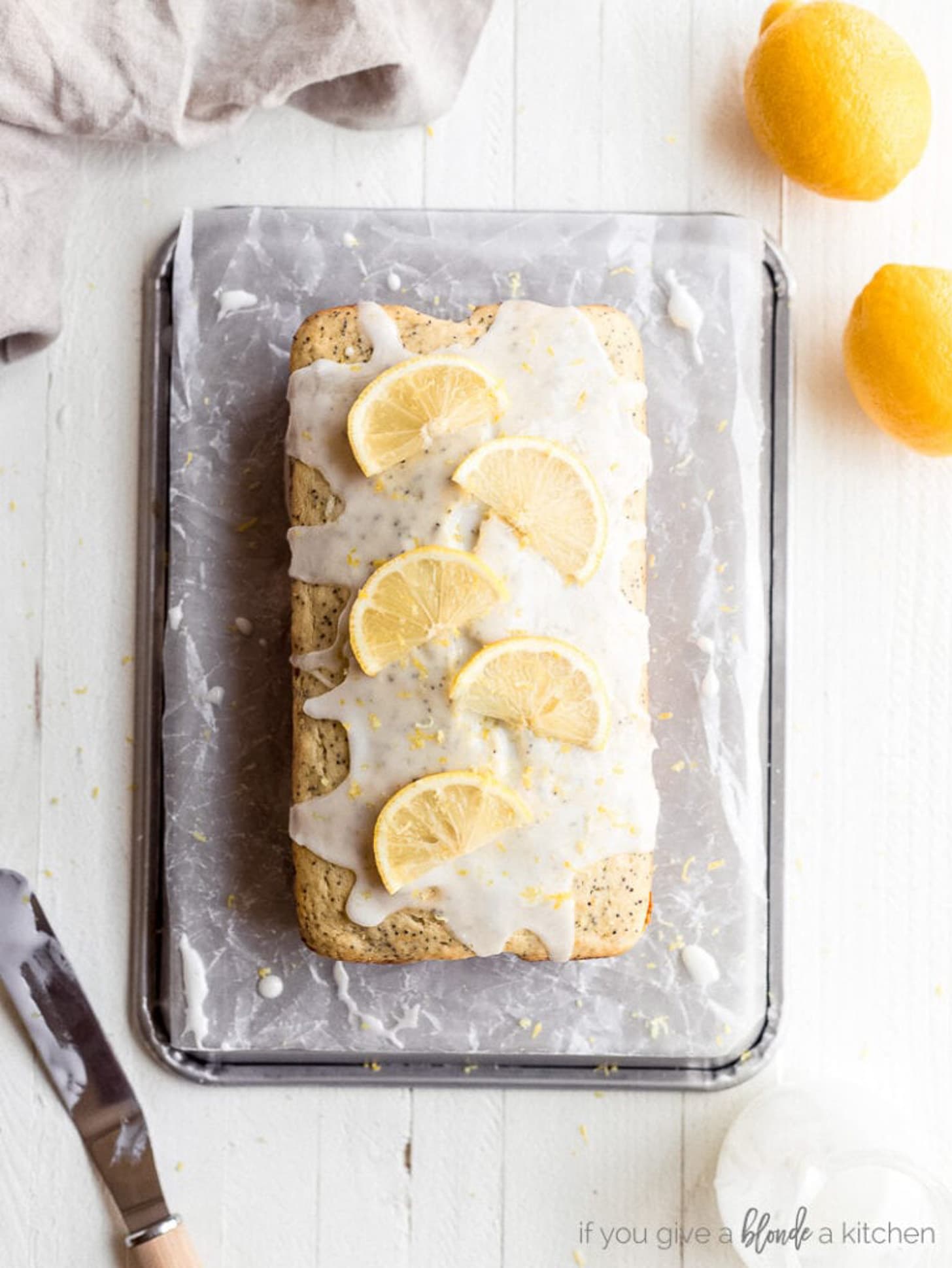 lemon poppy seed loaf with glaze and lemon slices on top.