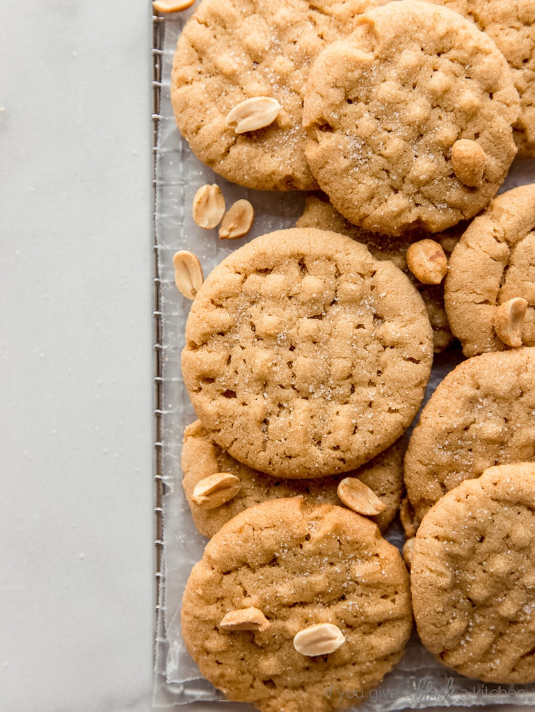 crisscross peanut butter cookies in pile with peanuts sprinkled on top