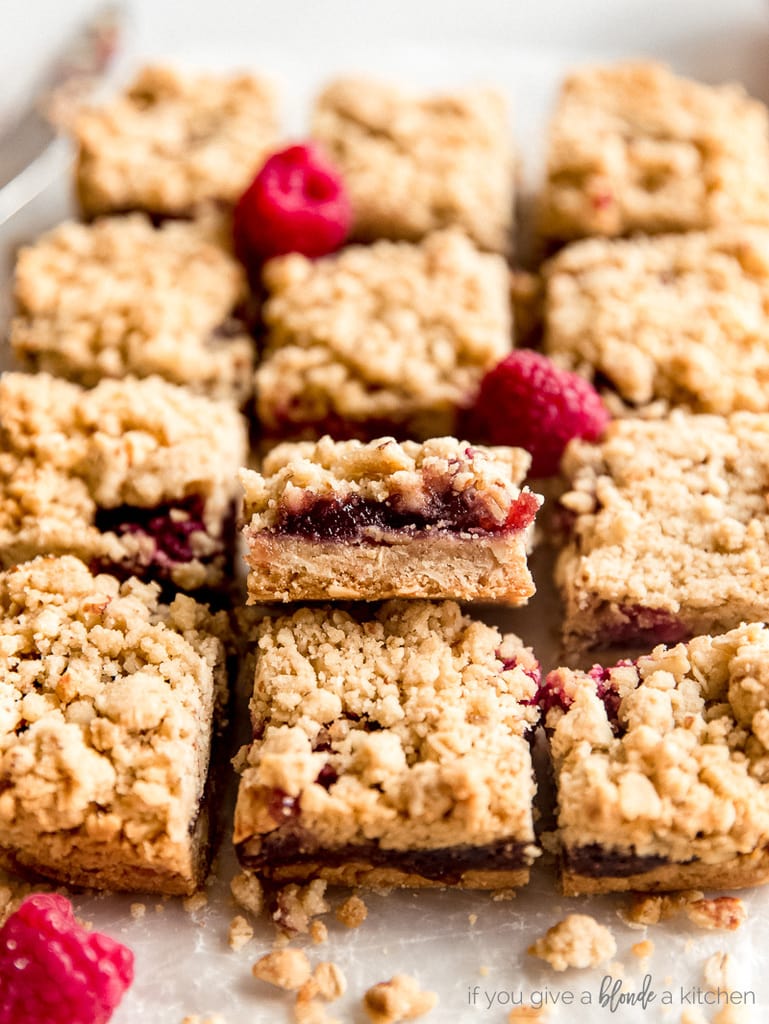 raspberry oatmeal bars with one propped up showing fruit filling