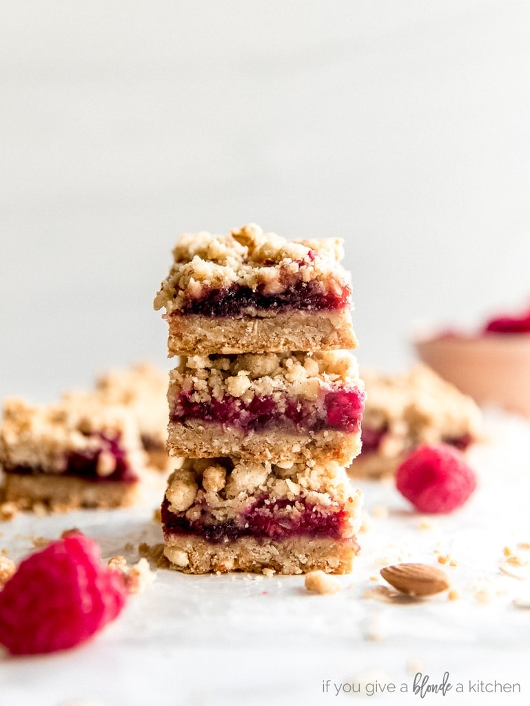 stack of three raspberry oatmeal bars with fresh raspberries next to it