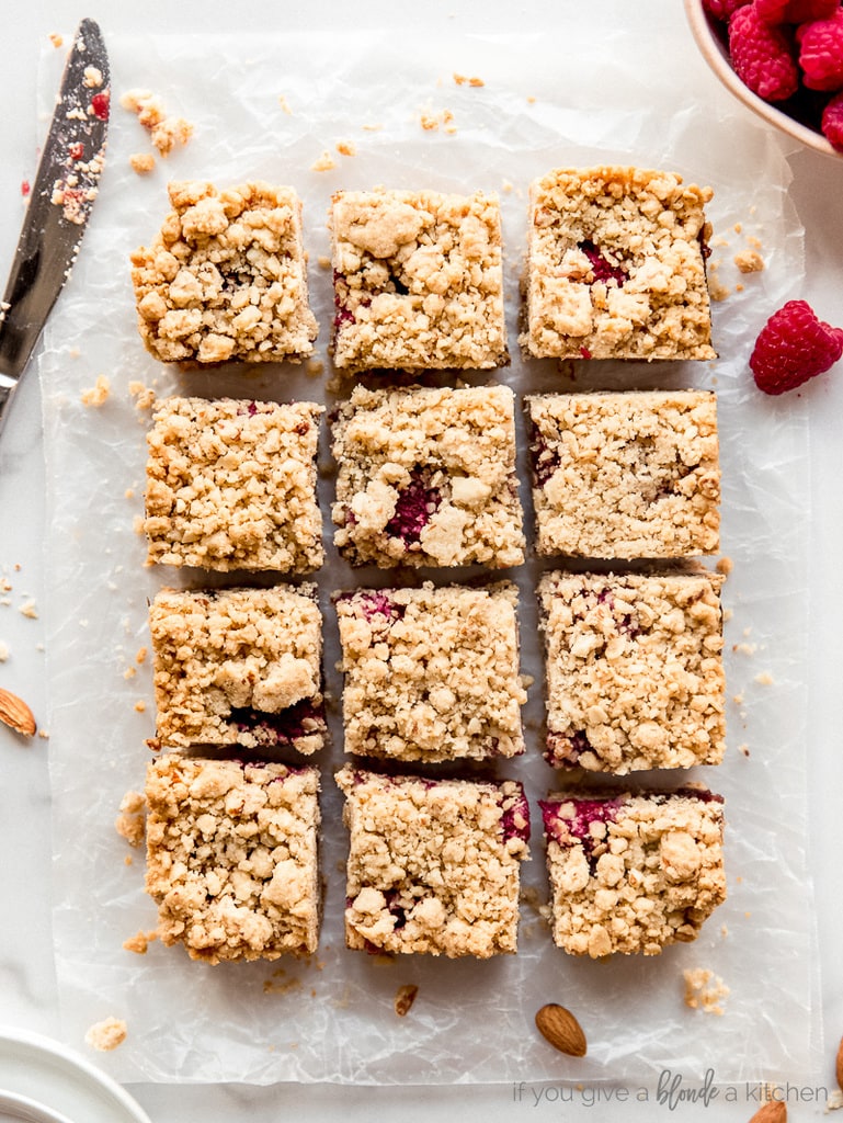 raspberry oatmeal bars cut into square on top of parchment paper