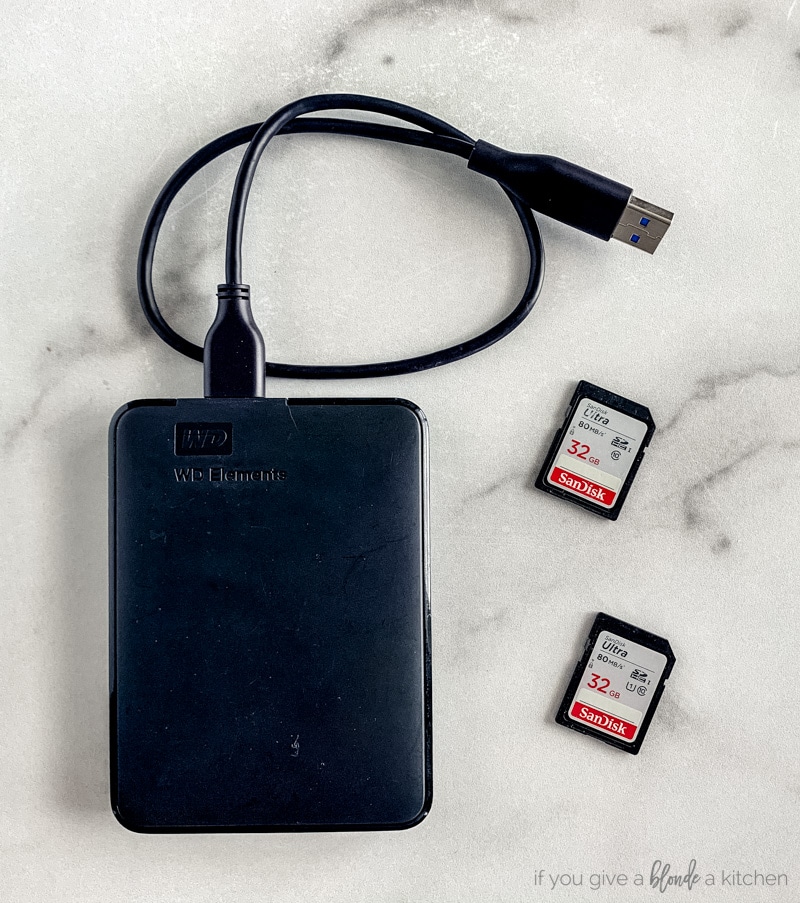 external 1TB hard drive and two 32 mb memory cards on marble surface