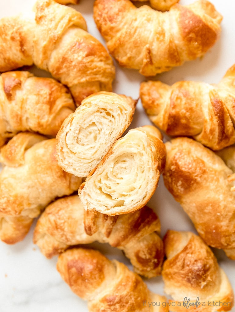 croissants on white surface and one croissant cut open showing layers inside