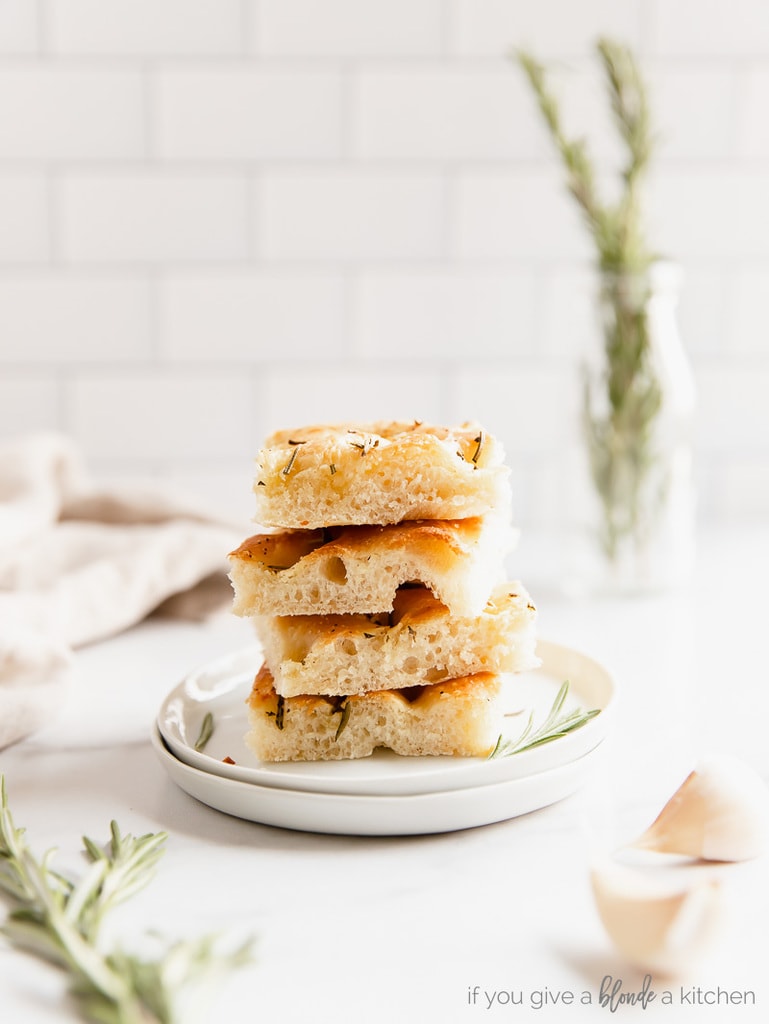 stack of four focaccia bread squares stack on top of each other on small white plate