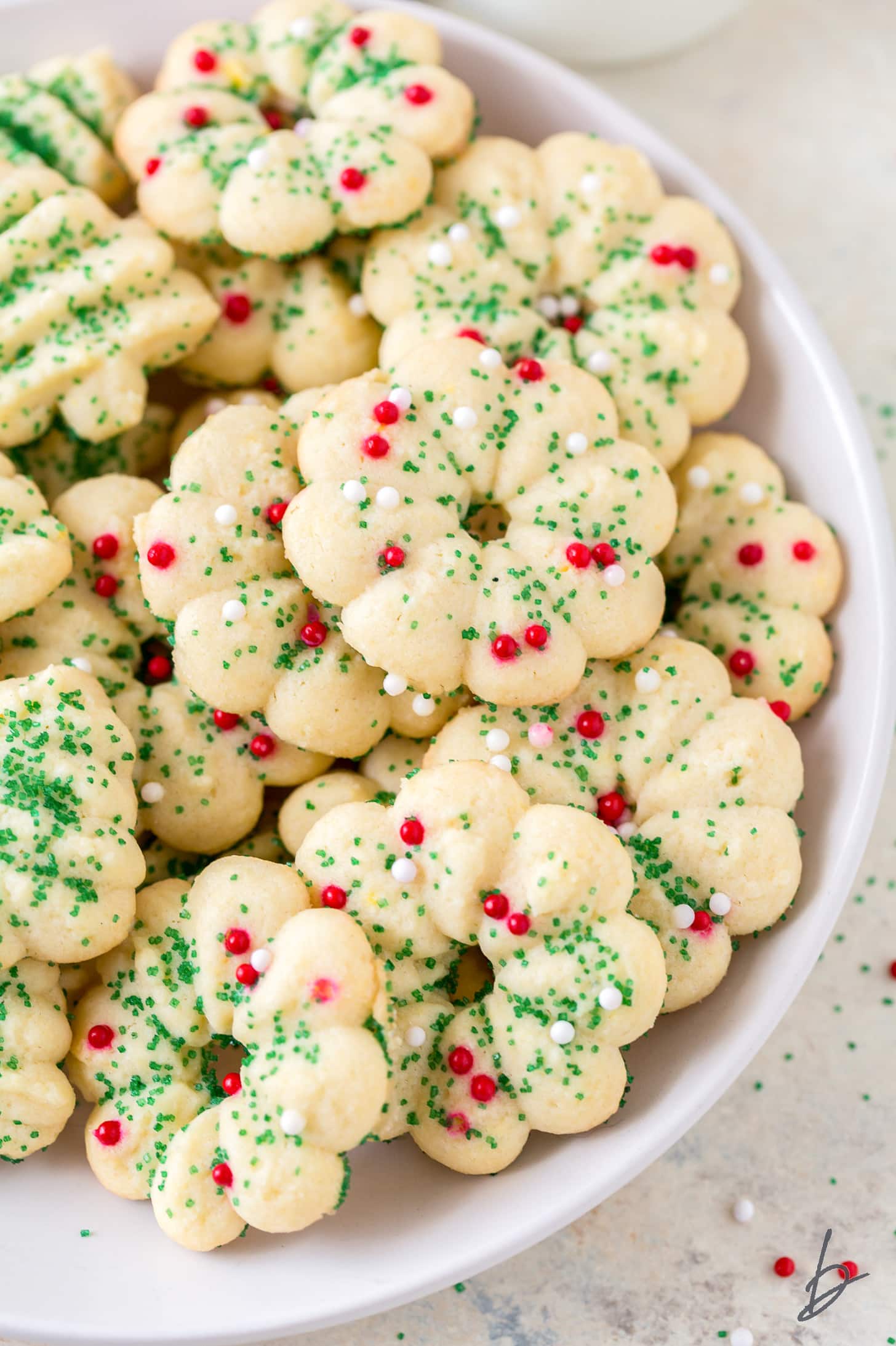 butter spritz cookies decorated with green sugar sprinkles and red nonpareils on white plate