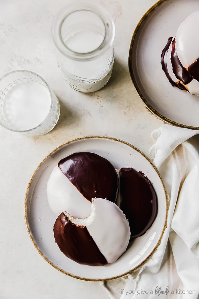 two plates of black and white cookies; glass bottle of milk and glass with milk next to plates