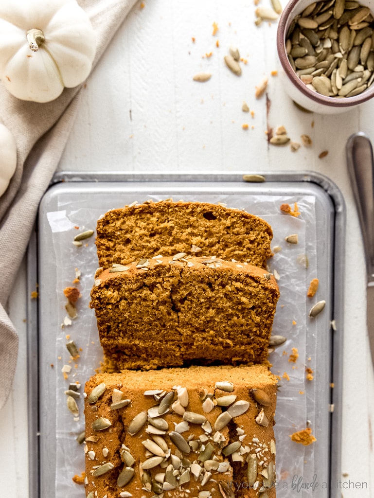 pumpkin bread with two slices cut off on top of crinkled parchment paper