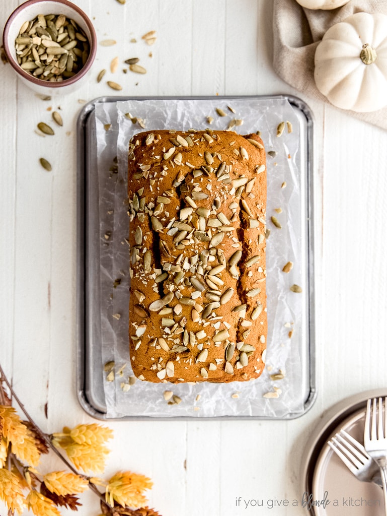 loaf of pumpkin bread topped with pumpkin seeds on top of baking sheet