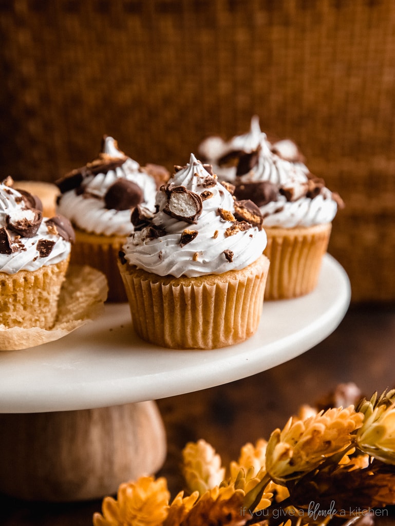 maple cupcakes with marshmallow frosting on marble cake stand on dark brown tabletop with leaves