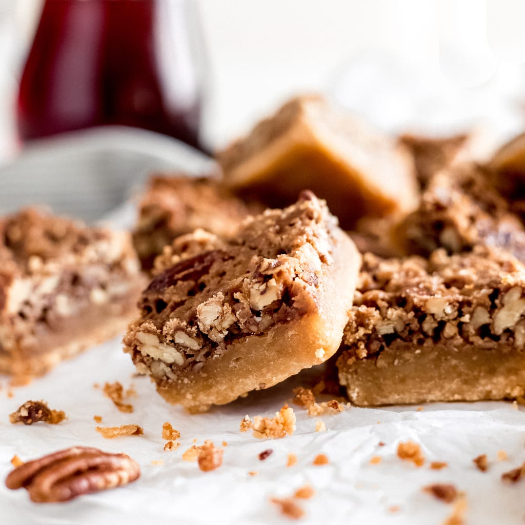 maple pecan bar propped up on another bar both showing shortbread crust and pecan layers