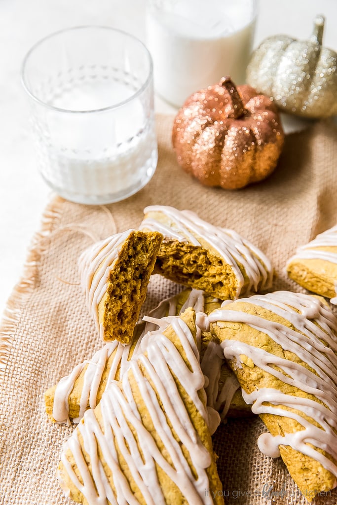 pumpkin scone broken in half to show inside; more scones with drizzle on burlap