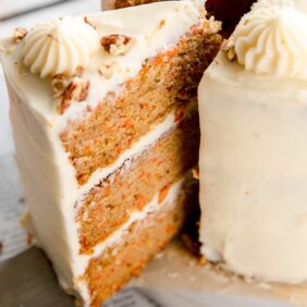 triple layer carrot cake slice with cream cheese frosting taken out of cake