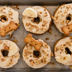 six dog donuts with frosting on a baking sheet
