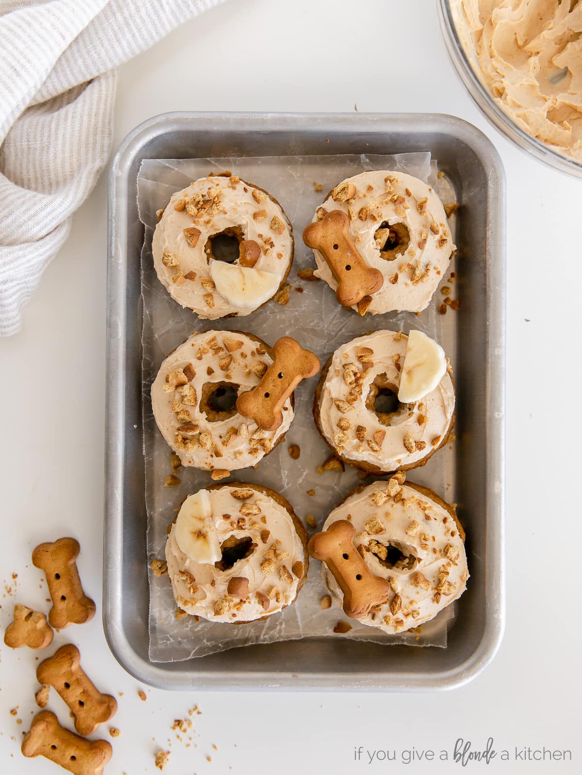 six dog donuts with frosting and biscuits on top