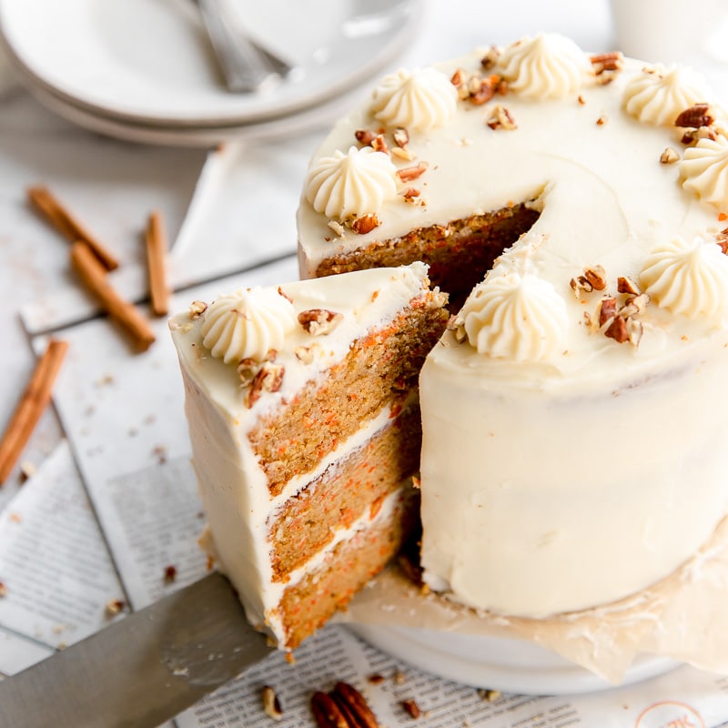 slice of triple layer carrot cake taken out of round cake