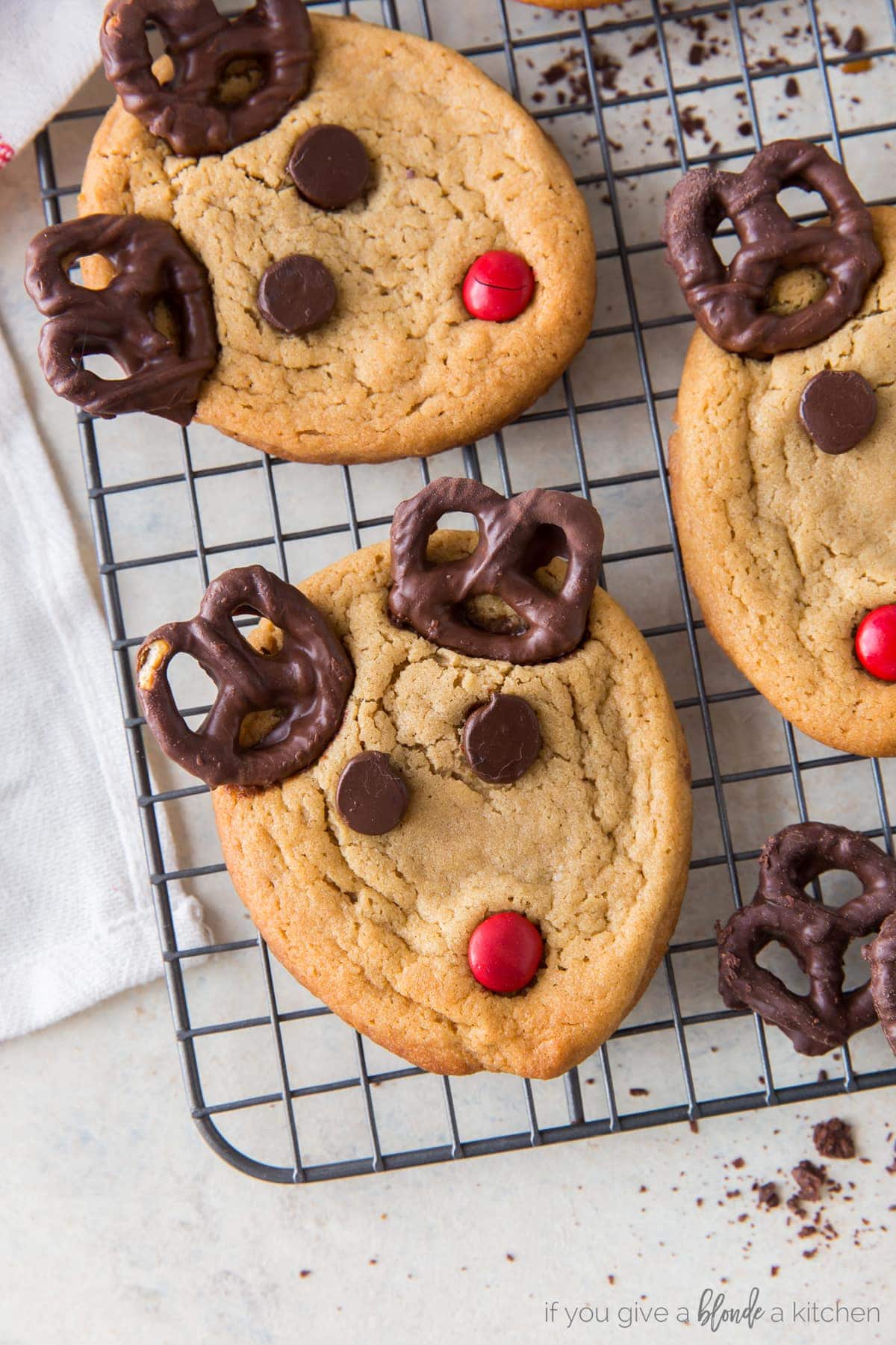 peanut butter reindeer cookie with two chocolate covered reindeer antlers, chocolate chip eyes and red m&m nose.