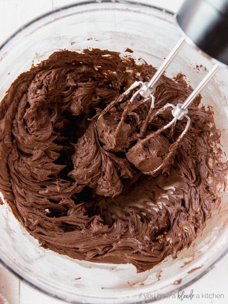 bowl of chocolate frosting with beaters of hand mixer in the frosting