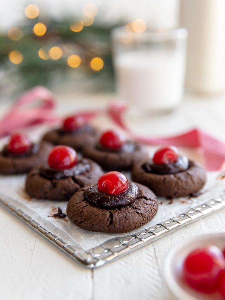 chocolate thumbprint cookies with chocolate ganache and maraschino cherries on wire cooling rack