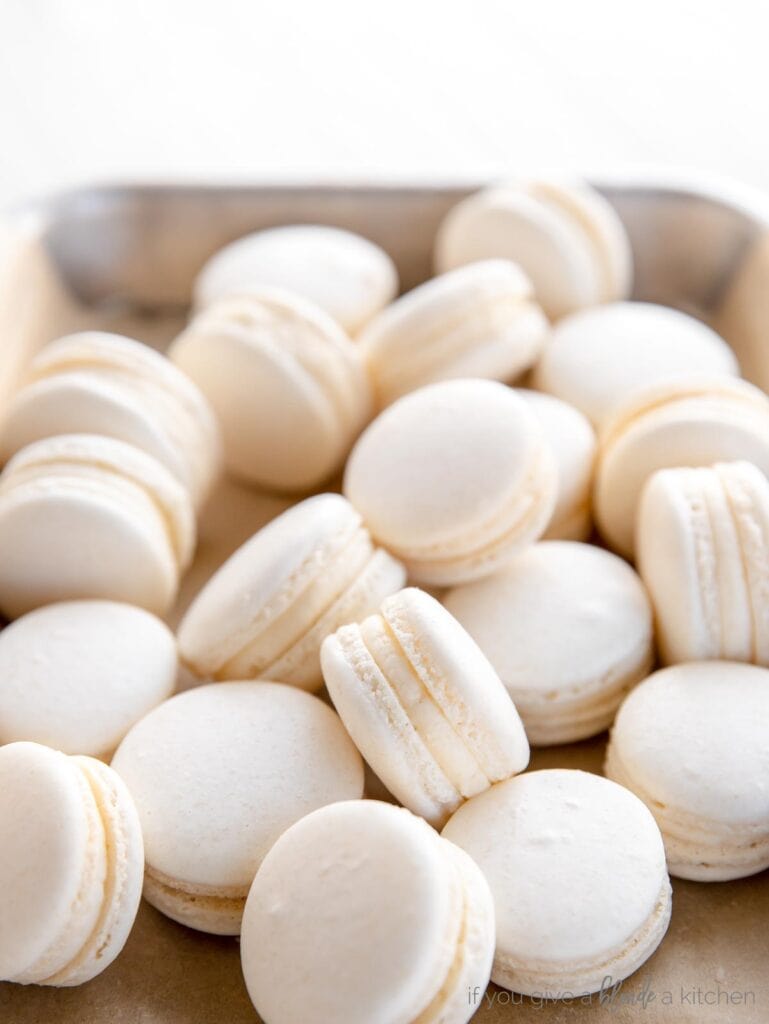 simple white macarons piled on a small baking sheet