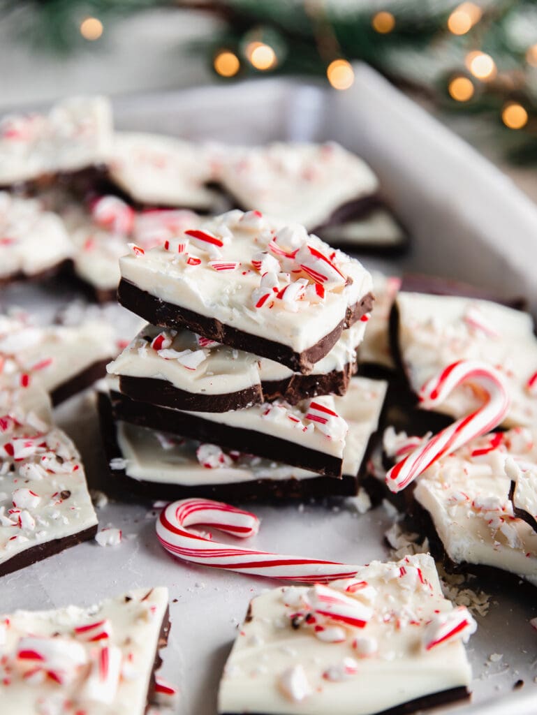 stack of peppermint bark pieces on tray next to mini candy cakes and more peppermint bark