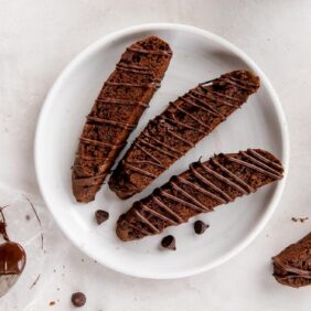 three chocolate biscotti on a white round plate