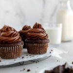 chocolate cupcakes with chocolate frosting on wire cooling rack with parchment paper