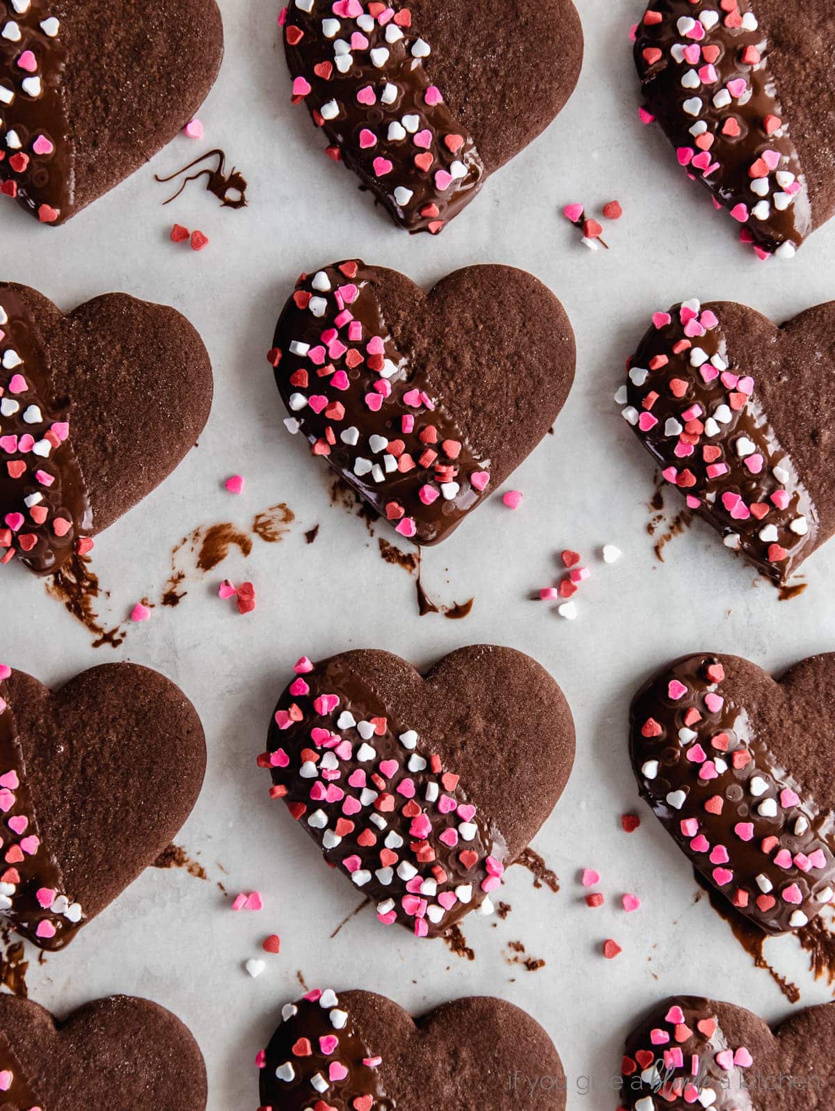 chocolate cut out cookies in a heart shape dipped in chocolate with red and pink sprinkles on tpo