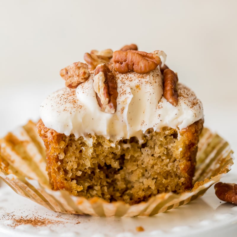 bite taken out of a hummingbird cupcakes with frosting and pecans.