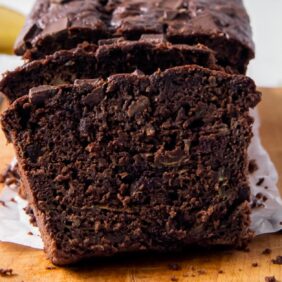 slice of chocolate zucchini banana bread leaned up against loaf