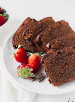 slices of chocolate pound cake on white plate with strawberries