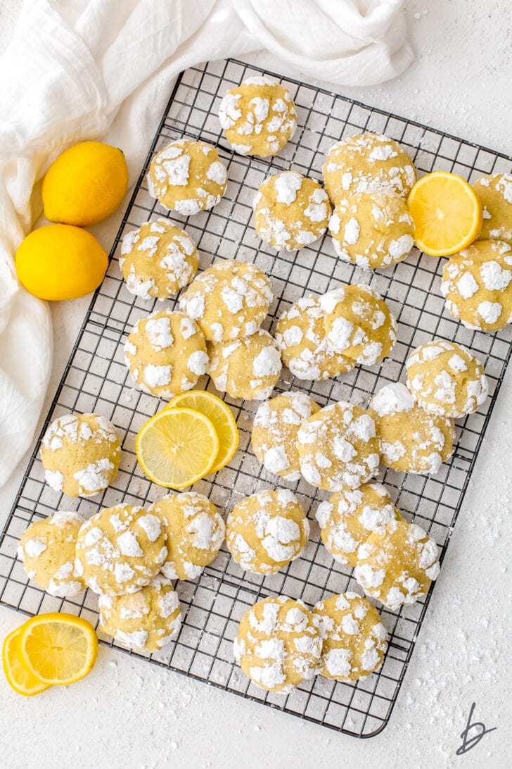 lemon crinkle cookies on wire cooling rack with lemons