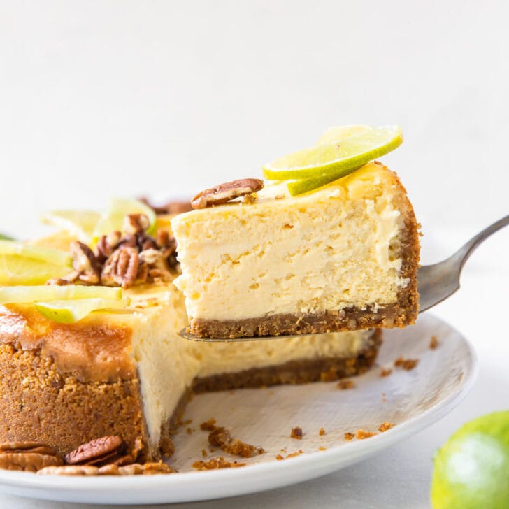 slice of lime curd cheesecake being lifted off plate with rest of cheesecake