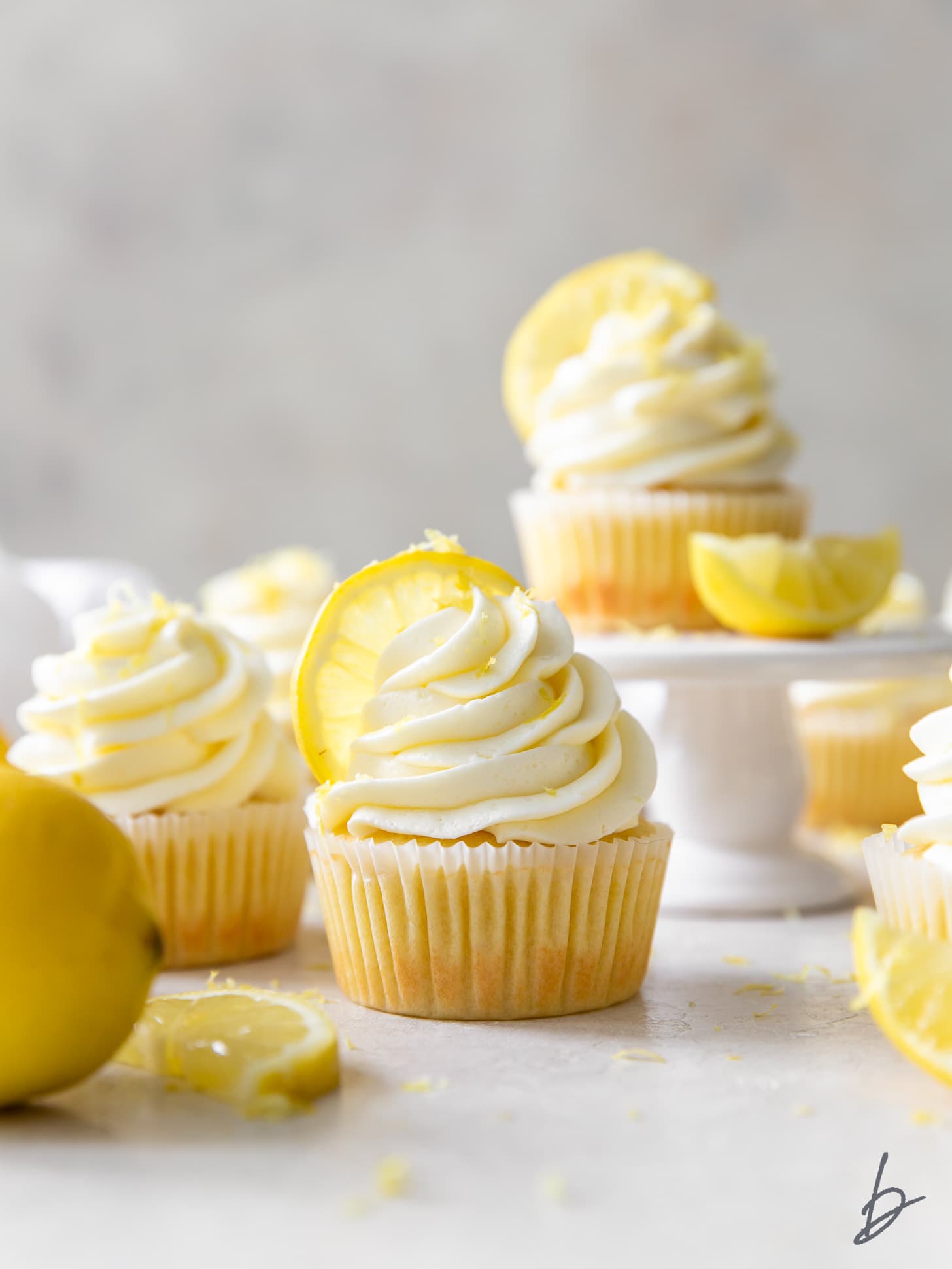 lemon cupcakes with frosting and lemon wedges as garnish.