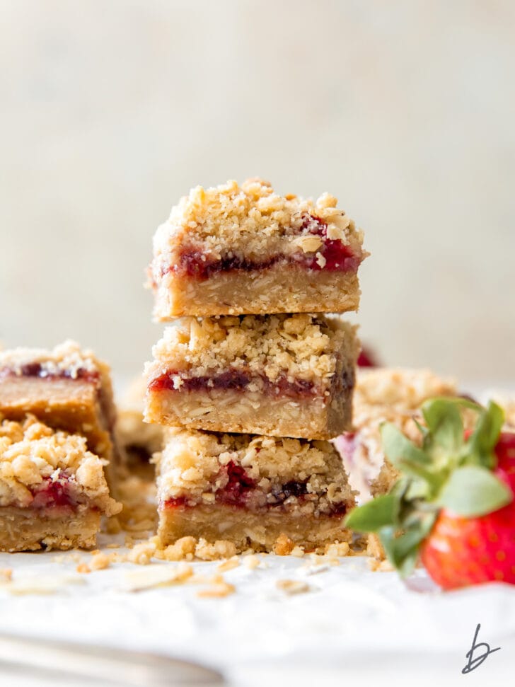 stack of three strawberry oatmeal bars showing layers of crust, strawberry preserves and oatmeal crumble topping