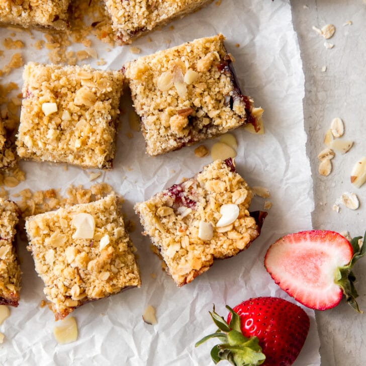 strawberry oatmeal bars on cut on parchment paper next to fresh strawberry