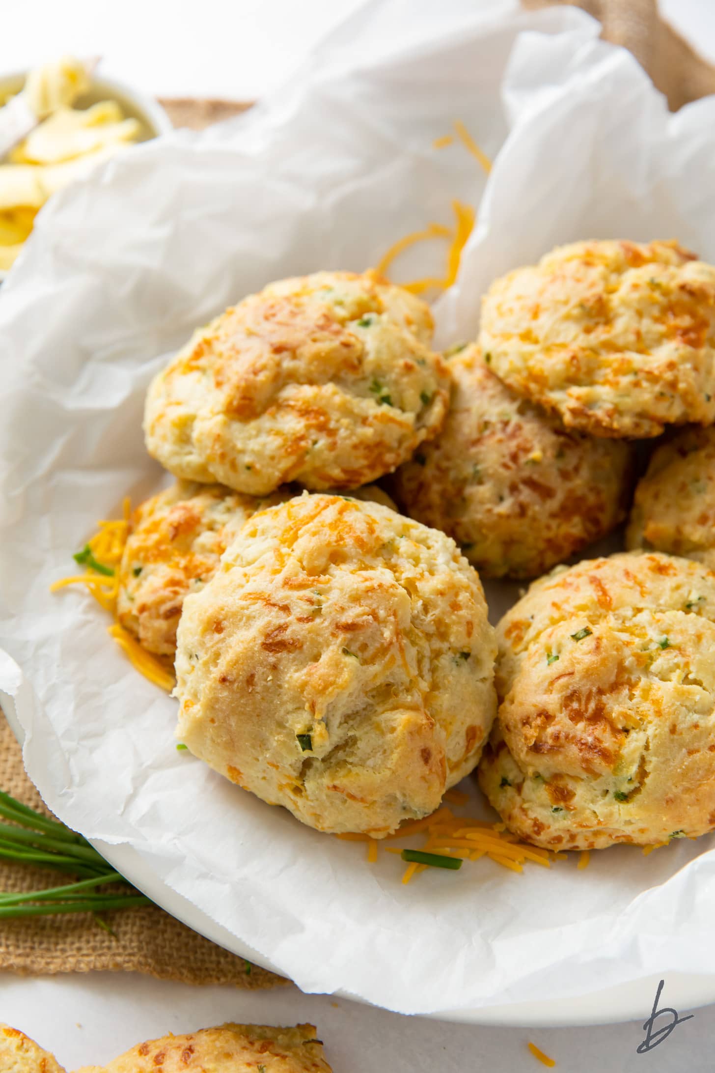 cheddar chive biscuits on crinkled parchment paper on plate