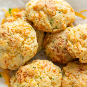 cheddar biscuits in a pile on crinkled parchment paper