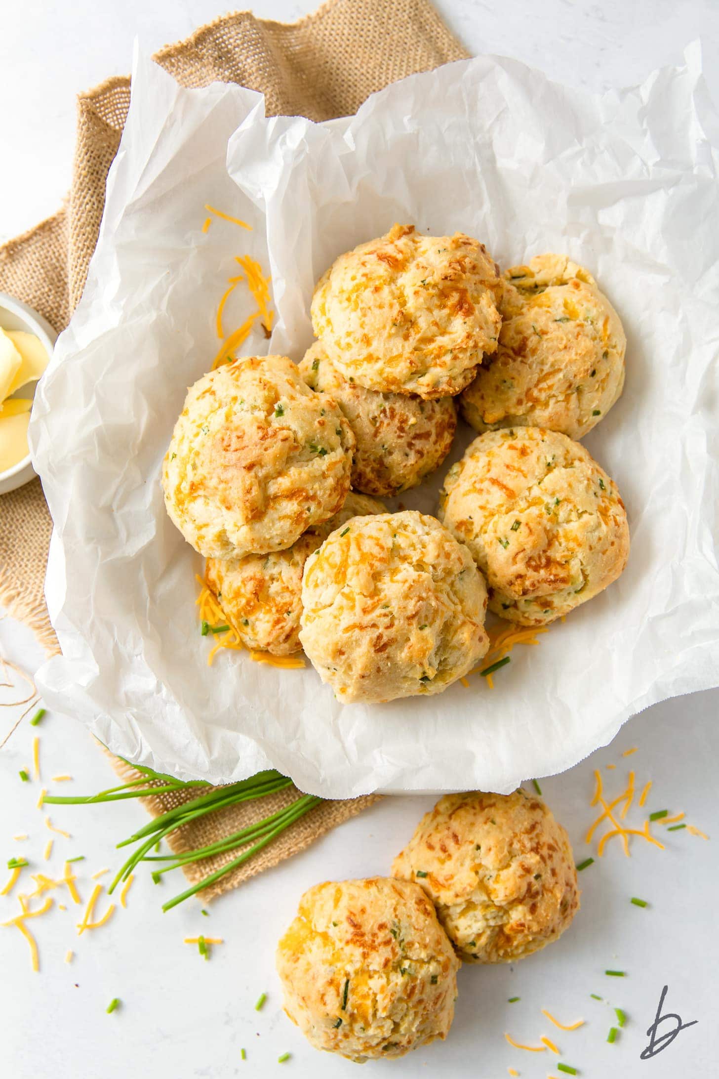cheddar drop biscuits on crinkled parchment paper on top of burlap cloth