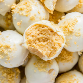 golden oreo truffle with bite on top of pile of more golden oreo truffles